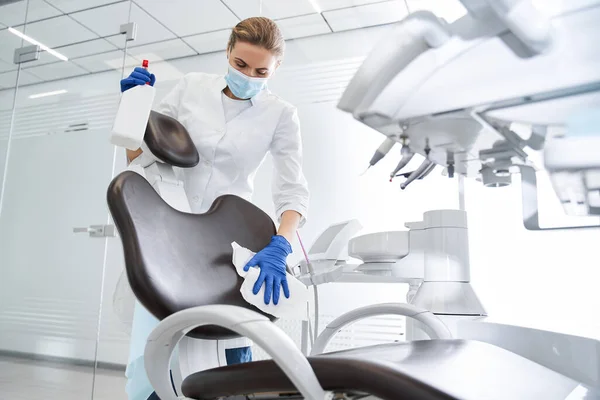 Стоматолог ретельно стерилізує медичне крісло всередині стоматологічної клініки — стокове фото