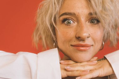 Çekingen bir gülümsemeyle kameraya bakan bir kadın.