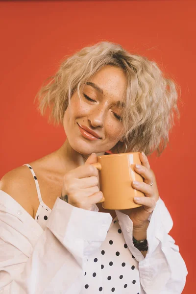 Mulher fecha os olhos e segurando xícara de café quente — Fotografia de Stock