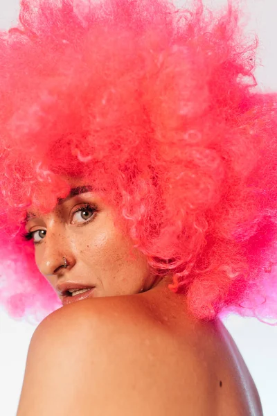 Mujer con peluca rosa mirando a la cámara sobre el hombro — Foto de Stock
