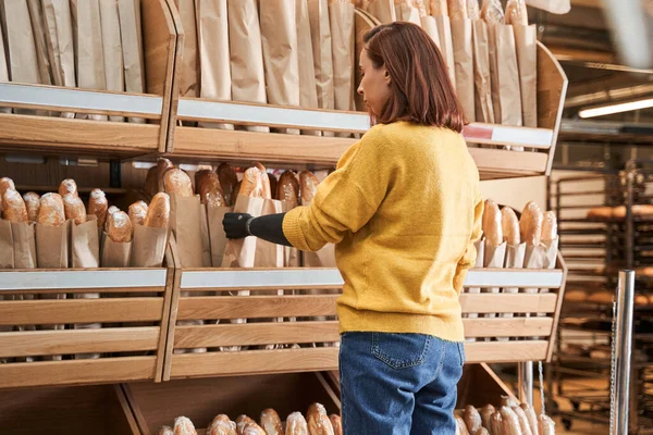 Girl standing in front of a row of bread at the supermarket — Stock Photo, Image