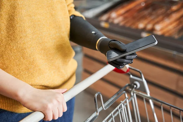 Žena s protézou nesoucí nákupní vozík v supermarketu — Stock fotografie