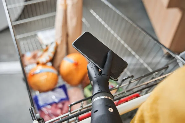 Mujer revisando la lista de compras en su teléfono inteligente en el supermercado — Foto de Stock