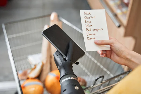 Mujer en el supermercado con estante de alimentos lectura lista de la compra — Foto de Stock