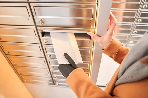 Woman with artificial limb putting envelope into mailbox