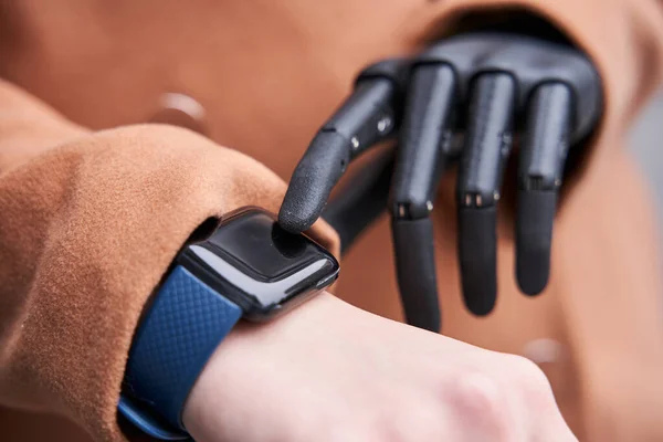 Женщина с имплантированной рукой смотрит на умные часы — стоковое фото