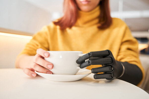 Female with prosthesis arm enjoying good rest at coffee shop