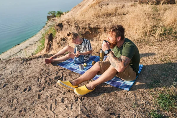 Twee personen die genieten van warme dranken terwijl ze aan de natuur zitten — Stockfoto