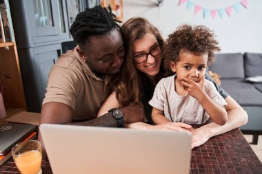 Dizüstü bilgisayarda anne babasıyla bir şey izlerken şoka uğrayan bir kız.