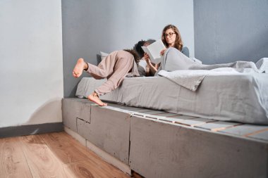 Kız yatakta oturuyor ve annesinin nasıl kitap okuduğunu dinlemeye hazırlanıyor.