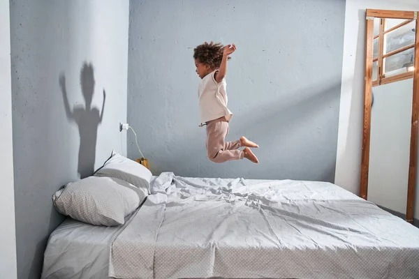 Meisje springen op het bed en het gevoel plezier terwijl het doorbrengen van tijd alleen op de slaapkamer — Stockfoto