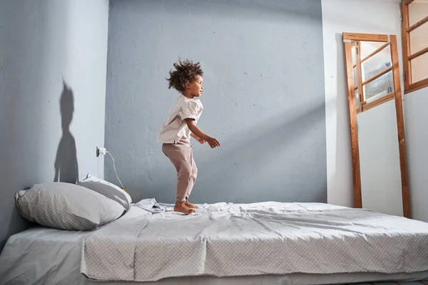 Gelukkig kind springen op het bed en genieten van de tijd voor zichzelf thuis — Stockfoto