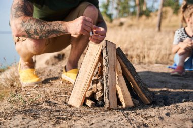 Kibritle tahta odunlardan ateş yakan adam.