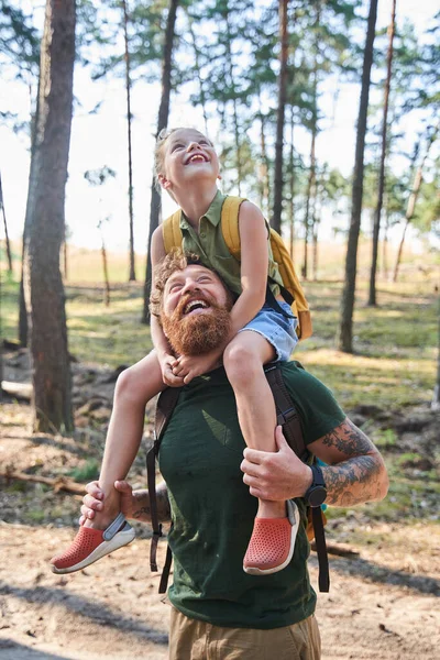 Девушка на шее своего отца ходит по лесу — стоковое фото