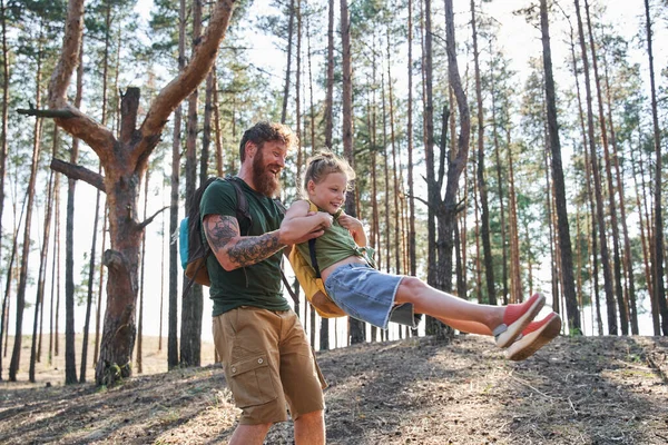 Muž otáčí svou dceru ve zbrani v lese — Stock fotografie