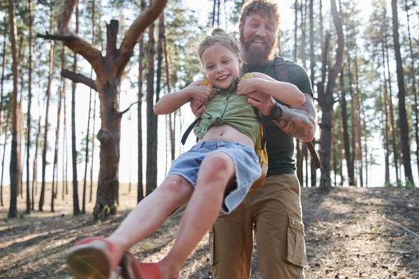 Muž otáčí svou dceru ve zbrani v lese — Stock fotografie