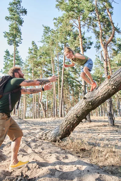 Flicka hoppar från fallna träd på sand i skogen — Stockfoto