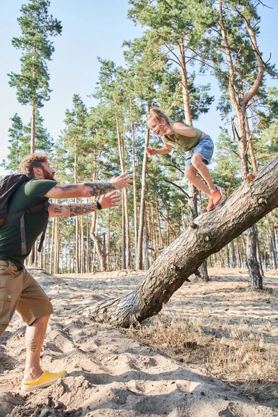 Dívka skákání z padlého stromu na písku v lese — Stock fotografie