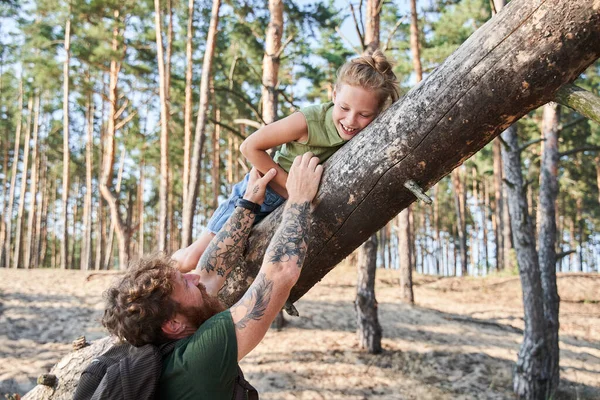 Άντρας που κρατάει την κόρη του σε πεσμένο δέντρο στο δάσος — Φωτογραφία Αρχείου