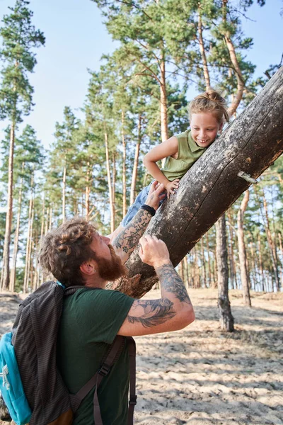 Άντρας που κρατάει την κόρη του σε πεσμένο δέντρο στο δάσος — Φωτογραφία Αρχείου