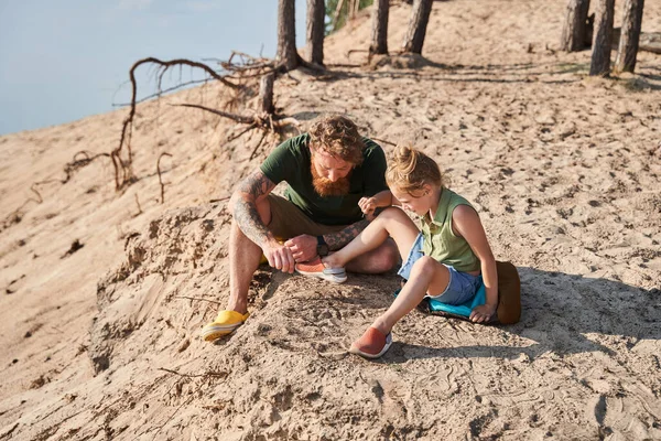 Vader en dochter tekenen op zand aan de kust — Stockfoto