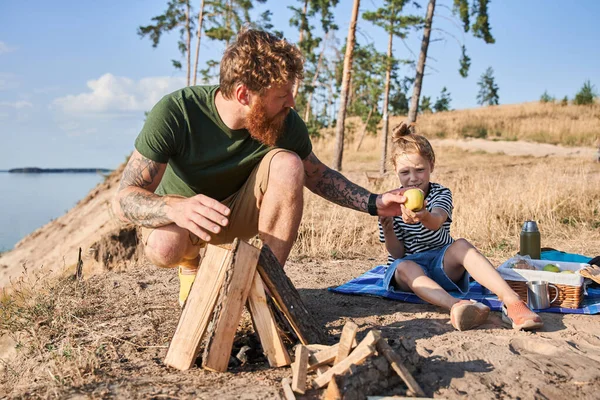 Man die vuur maakt en appel geeft aan zijn dochter — Stockfoto