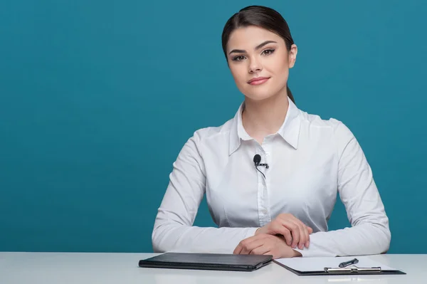 Hermosa chica de televisión presentador de noticias está informando sentado en la mesa — Foto de Stock