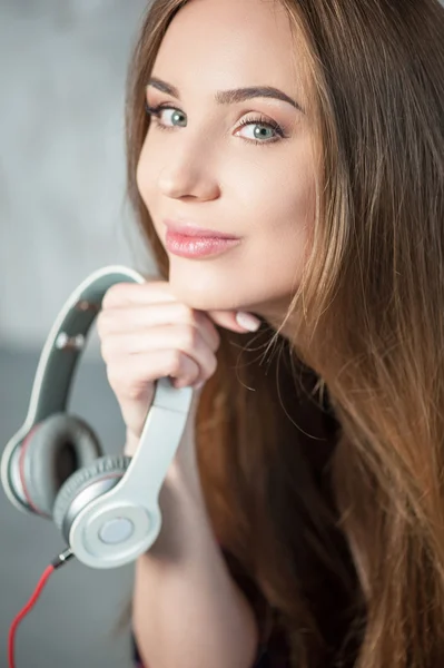 Mulher hipster alegre está segurando seus fones de ouvido — Fotografia de Stock