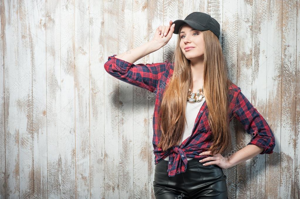 Pretty hipster woman with hat is standing near the wall