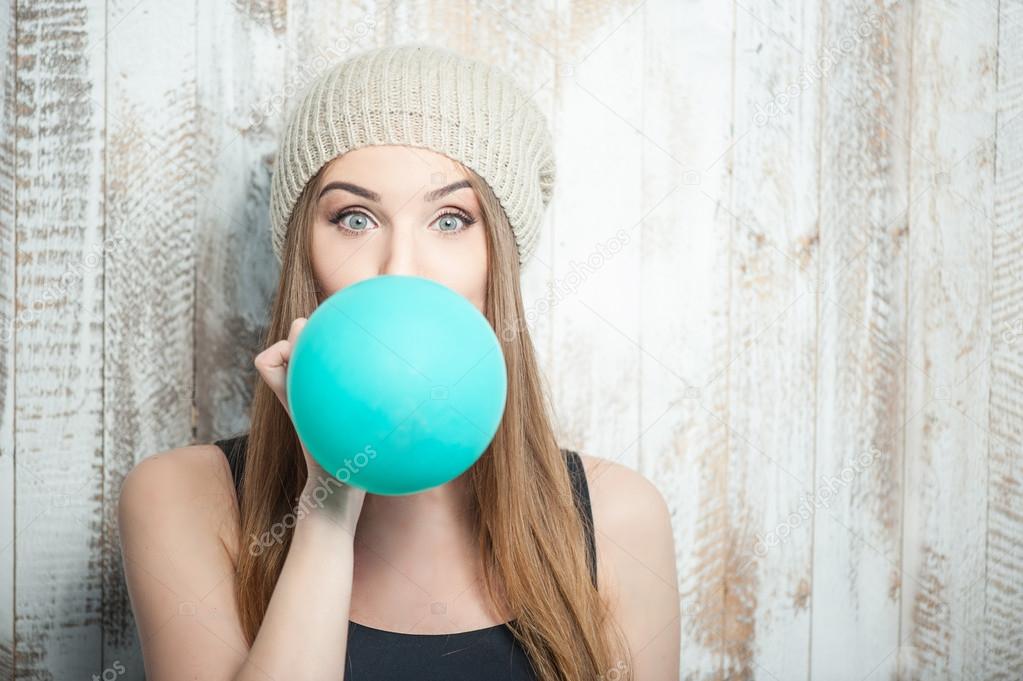 Pretty hipster woman is inflating colored balloon