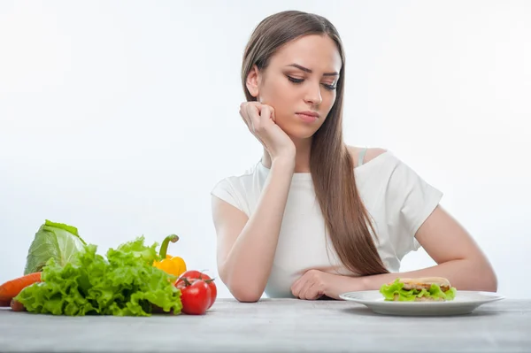 Bella giovane donna sta scegliendo tra cibo sano e dannoso — Foto Stock