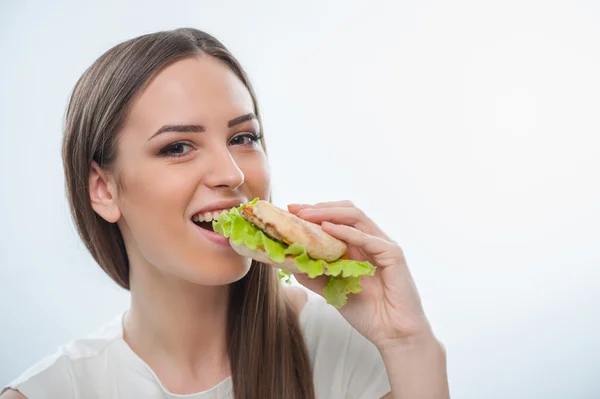 Cheerful young girl is biting unhealthy food — Stock Photo, Image