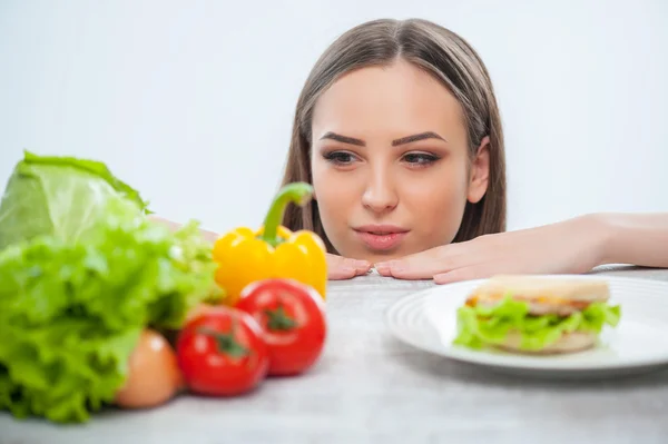 Krásná mladá dáma se rozhodne mezi zdravé a nezdravé potraviny — Stock fotografie