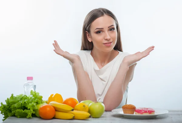 Menina bonita está escolhendo entre alimentos saudáveis e insalubres — Fotografia de Stock