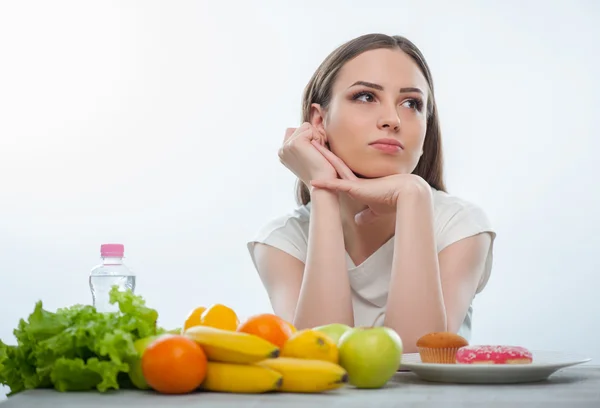 Menina bonita está escolhendo entre alimentos saudáveis e insalubres — Fotografia de Stock