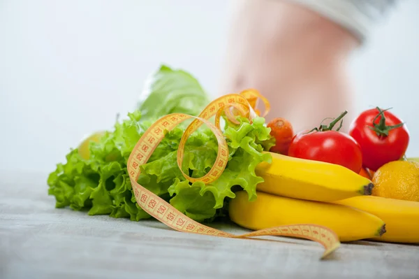 Fit girl is standing behind fruits and vegetables — Stock Photo, Image
