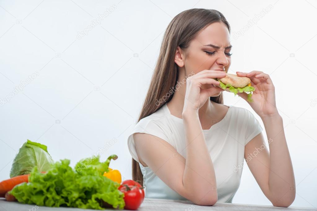 Beautiful young girl is eating unhealthy food