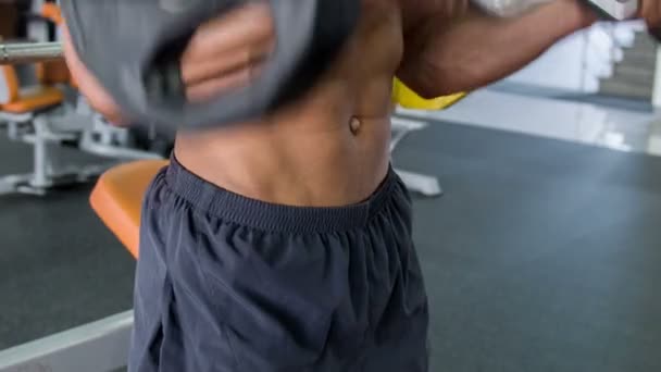 Atractivo joven deportista está levantando pesas en el gimnasio — Vídeo de stock