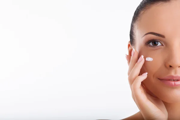 Atractiva chica sana está aplicando crema hidratante en su cara —  Fotos de Stock