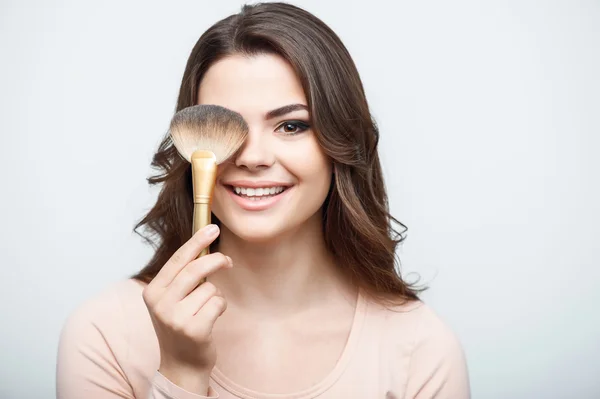 Pretty young woman is doing her make-up — Stockfoto