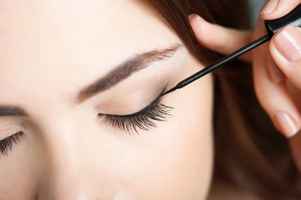 Pretty young woman is doing her make-up — Stock fotografie