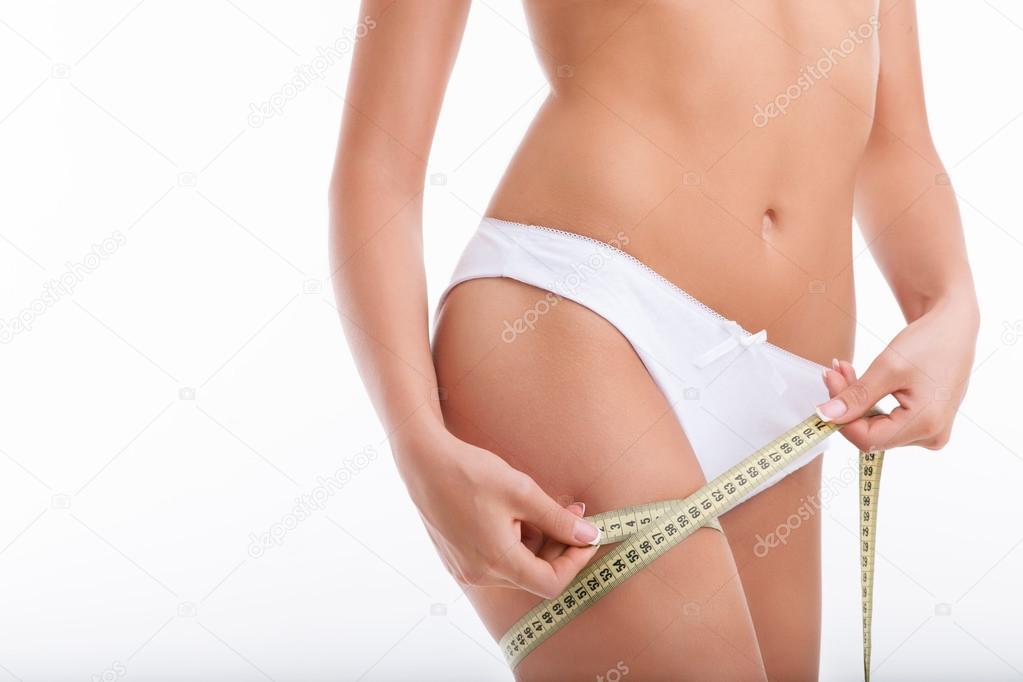 Young healthy woman is measuring her figure