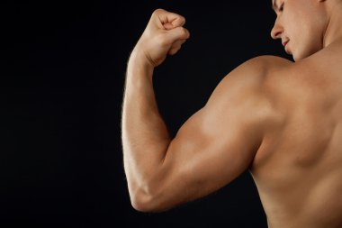 Attractive young bodybuilder is showing his muscles