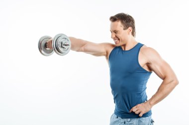 Cheerful young sportsman is exercising with iron equipment