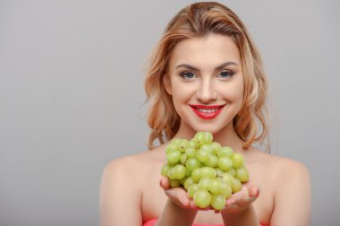 Cheerful young girl is presenting fresh green fruit