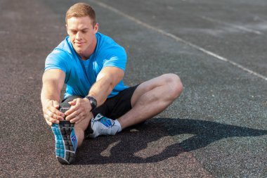 Cheerful young man is warming up before running
