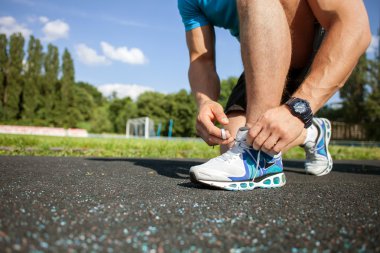 Healthy young athlete is preparing his sneakers for training
