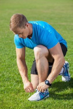 Handsome young athlete is preparing his sneakers before running