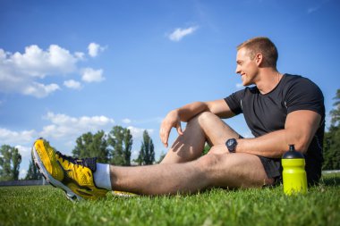 Cheerful young sportsman is resting after running