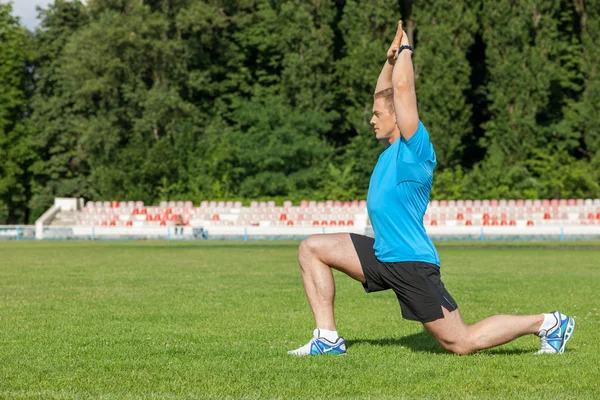 Atractivo joven deportista está haciendo calentamiento en la hierba — Foto de Stock